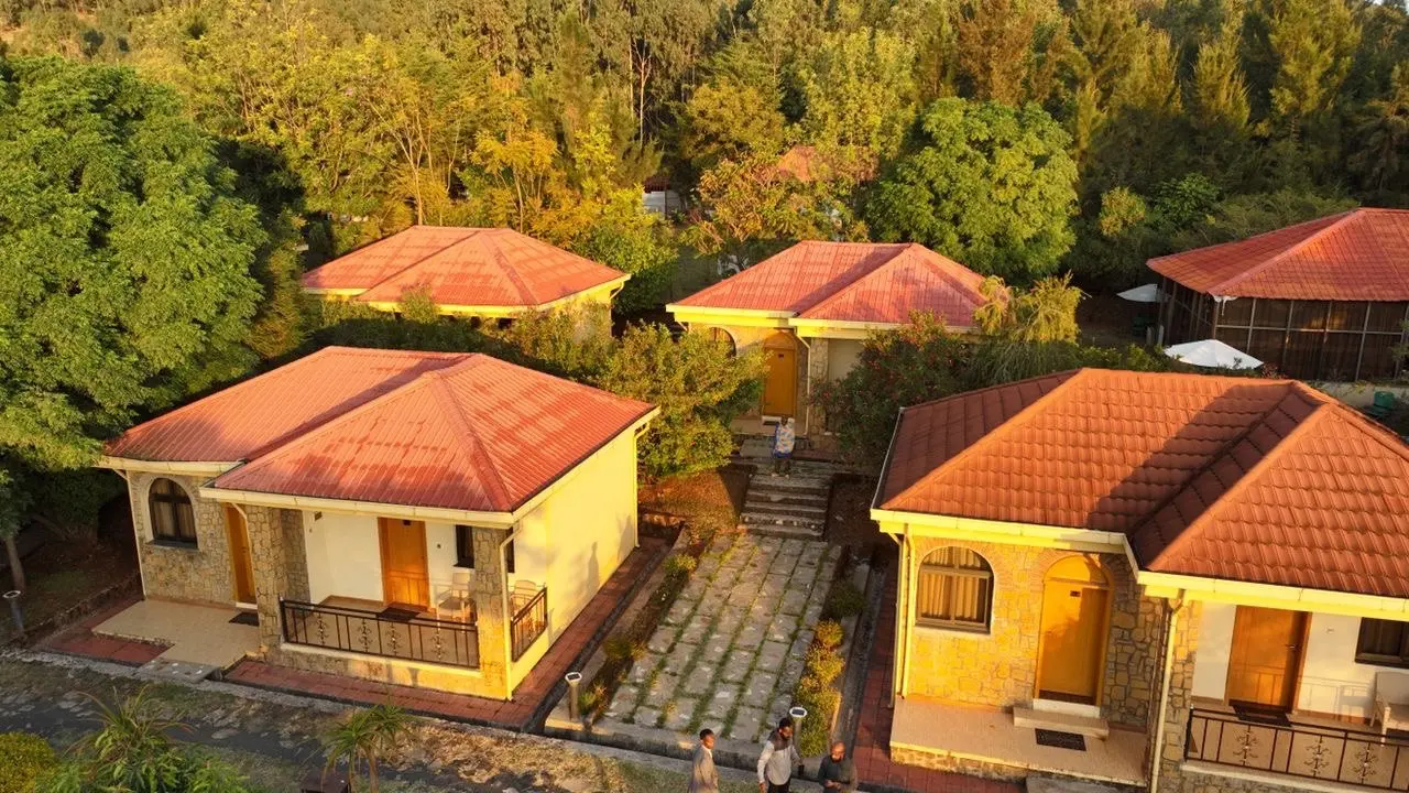 Aerial view of cream and stone guest villas with red tile roofs among trees