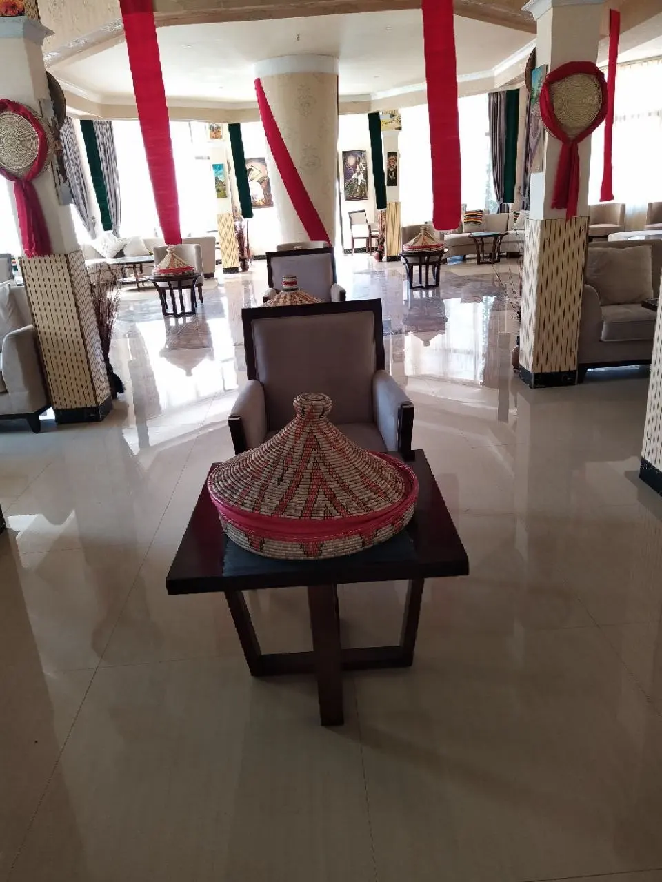 Lounge with a woven injera basket on a low table and red drapes beyond