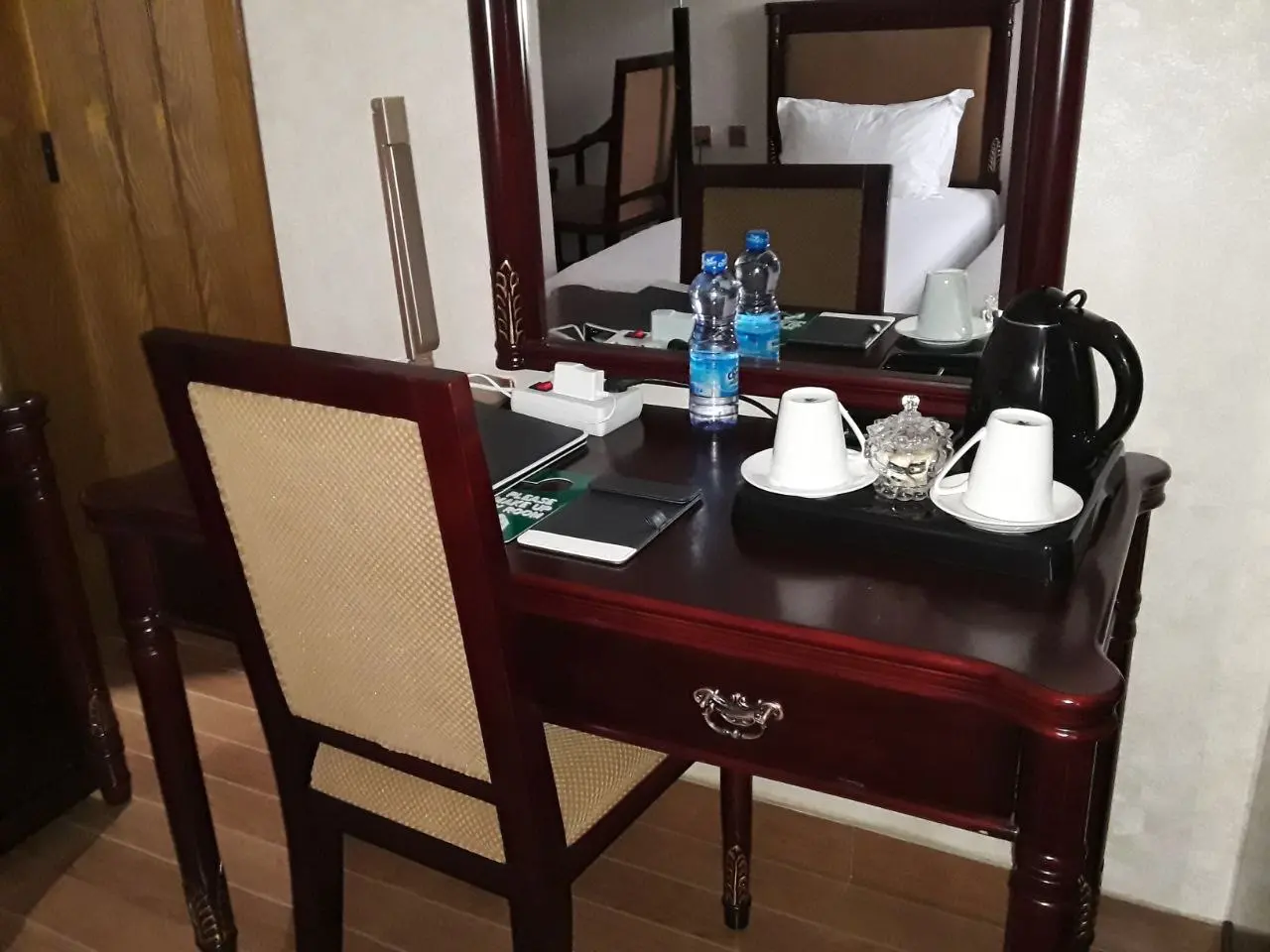 Room desk with a mirror, a kettle, cups and bottled water