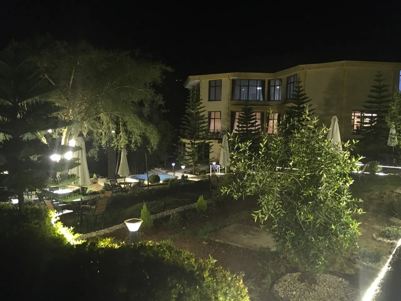 Guest building and garden lit up at night among pine trees